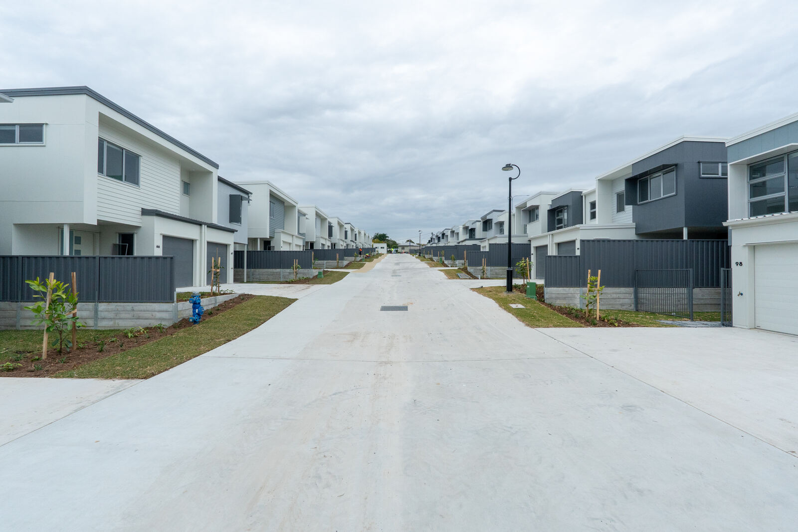 Long street view of a completed multi-dwelling development with matching fencing across every unit