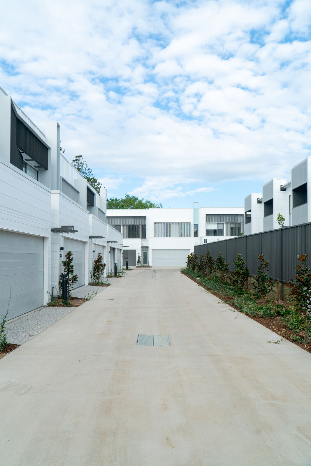 Street view down a row of completed townhouses with custom aluminium fencing and screening
